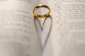 A wedding Ring on the bible with shadow of heart shape on the page