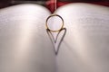 A wedding Ring on the bible with shadow of heart shape on the page