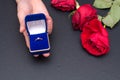 Wedding ring in box in hand with red roses flower on black background Royalty Free Stock Photo