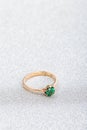 Wedding ring with emerald green gemstone on white sparkle background Royalty Free Stock Photo