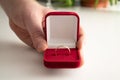 Wedding ring red box surrounded by rose petals. An offer of marriage. Box with a ring in the hands of a man on a blurred Royalty Free Stock Photo