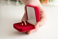 Wedding ring red box surrounded by rose petals. An offer of marriage. Box with a ring in the hands of a man on a blurred Royalty Free Stock Photo