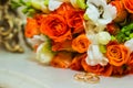 Wedding ring. Two gold vintage rings and a bride`s bouquet of orange roses and white flowers Royalty Free Stock Photo