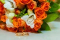Wedding ring. Two gold vintage rings and a bride`s bouquet of orange roses and white flowers Royalty Free Stock Photo