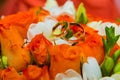 Wedding ring. Two gold vintage rings and a bride`s bouquet of orange roses and white flowers Royalty Free Stock Photo