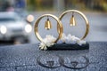Wedding rings with bells in drops of rain on the roof of the car