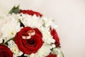 Wedding rings and bouquet of red and white flowers. light background with copy space Royalty Free Stock Photo