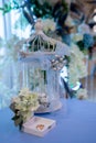 Wedding rings in a box decorated with flowers, decorative birdcage, floral decor in the background