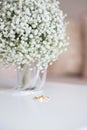 Wedding rings and a bridal bouquet over a white table Royalty Free Stock Photo