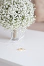 Wedding rings and a bridal bouquet over a white table Royalty Free Stock Photo