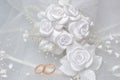 Wedding rings on bridal veil with white boutonniere on gray Royalty Free Stock Photo