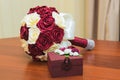 Wedding rings of the bride and groom on a Beautiful wedding bouquet of red and white roses. Wooden box for wedding rings Royalty Free Stock Photo