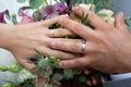 Wedding rings and bride groom hands over flowers bouquet for marriage Royalty Free Stock Photo