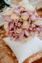 Wedding rings of the bride and groom on a silk pillow for rings next to a wedding bouquet of roses and lilies Royalty Free Stock Photo