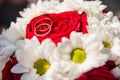 Wedding rings are on the bride`s bouquet. Wedding bouquet of white daisies and red roses. Wedding background for cards and Royalty Free Stock Photo