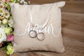 Wedding rings on brown natural pillow with ribbon on wooden table with amour text means love in french and flowers marriage