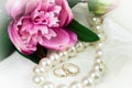 Wedding rings, pearl necklace and peony flower. Royalty Free Stock Photo