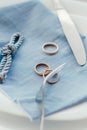 Wedding rings, diamond ring, fork, knife, blue napkin, a piece of cord with a sea knot Royalty Free Stock Photo