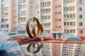 Wedding rings, flowers and ribbon on the roof of the car on the background of city buildings Royalty Free Stock Photo