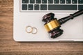 Wedding rings and judge gavel on computer laptop, wooden background, top view