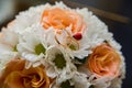 Wedding rings lie on a bouquet of orange roses and white colors. Ladybug. Royalty Free Stock Photo