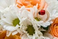 Wedding rings lie on a bouquet of orange roses and white colors. Ladybug. Royalty Free Stock Photo