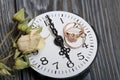 Wedding rings lie on the dial of the watch. Nearby dried roses. On brushed pine boards painted in black and white Royalty Free Stock Photo