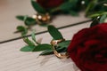 Wedding rings lie near a bouquet of white and red roses with a ribbon, on an old wooden table Royalty Free Stock Photo