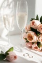 Wedding rings lie next to two glasses of champagne and a bouquet of roses Royalty Free Stock Photo