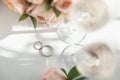 Wedding rings lie next to two glasses of champagne and a bouquet of roses Royalty Free Stock Photo