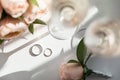 Wedding rings lie next to two glasses of champagne and a bouquet of roses Royalty Free Stock Photo