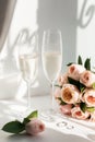 Wedding rings lie next to two glasses of champagne and a bouquet of roses Royalty Free Stock Photo