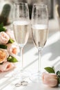 Wedding rings lie next to two glasses of champagne and a bouquet of roses Royalty Free Stock Photo