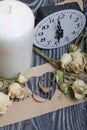 Wedding rings lie on paper with a cut out heart. Nearby are dried roses and a clock. On brushed pine boards painted in black and Royalty Free Stock Photo