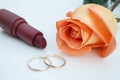 Wedding rings, lipstick and orange rose, on white background Royalty Free Stock Photo