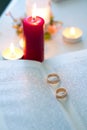 Wedding rings on an old book near red candle Royalty Free Stock Photo