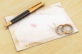 Wedding rings, pen and empty card on wooden table Royalty Free Stock Photo