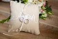 Wedding rings on a pillow with ribbon on wooden table with amour text means love in french