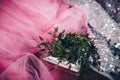 Wedding rings on a pink cloth in a wreath of green, silver in the background