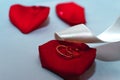 Wedding rings on a red rose petal with a white satin ribbon on the table Royalty Free Stock Photo