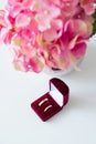 Wedding rings in a red velvet box and a bridal bouquet over a white table, flat lay top-down composition Royalty Free Stock Photo