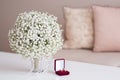 Wedding rings in a red velvet box and a bridal bouquet over a white table Royalty Free Stock Photo