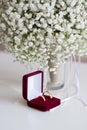 Wedding rings in a red velvet box and a bridal bouquet over a white table Royalty Free Stock Photo