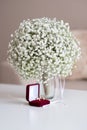 Wedding rings in a red velvet box and a bridal bouquet over a white table Royalty Free Stock Photo