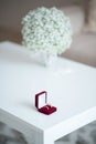 Wedding rings in a red velvet box and a bridal bouquet over a white table Royalty Free Stock Photo