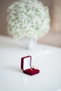 Wedding rings in a red velvet box and a bridal bouquet over a white table Royalty Free Stock Photo