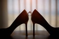 Wedding rings stand before bottle of parfume between classy white woman shoes