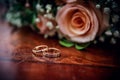 Wedding rings on a table with a Rose bouquet at the background