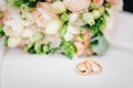 Wedding rings on white surface against flowers Royalty Free Stock Photo