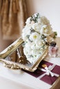 Wedding rustic bouquet, decorative mirrored tray, bottle of perfume and envelope letter with stamp on nightstand. Bridal room inte